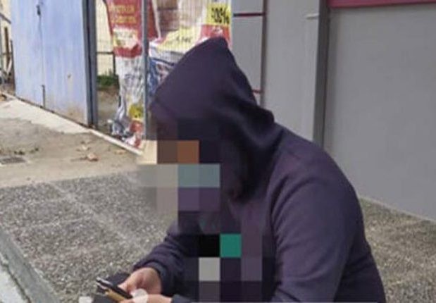 Μαθητής παρακολουθεί τα μαθήματά του στο πεζοδρόμιο έξω από καφενείο